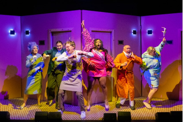 The cast of The Grand Old Opera House Hotel. Six people stand and pose in multicoloured outfits.